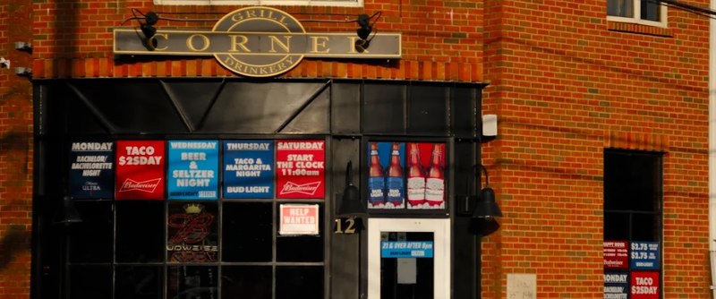 Corner&rsquo;s storefront at 12 E Park Place: the Corner Grill & Drinkery sign over the black front, the weekly specials board in the windows, and the door.